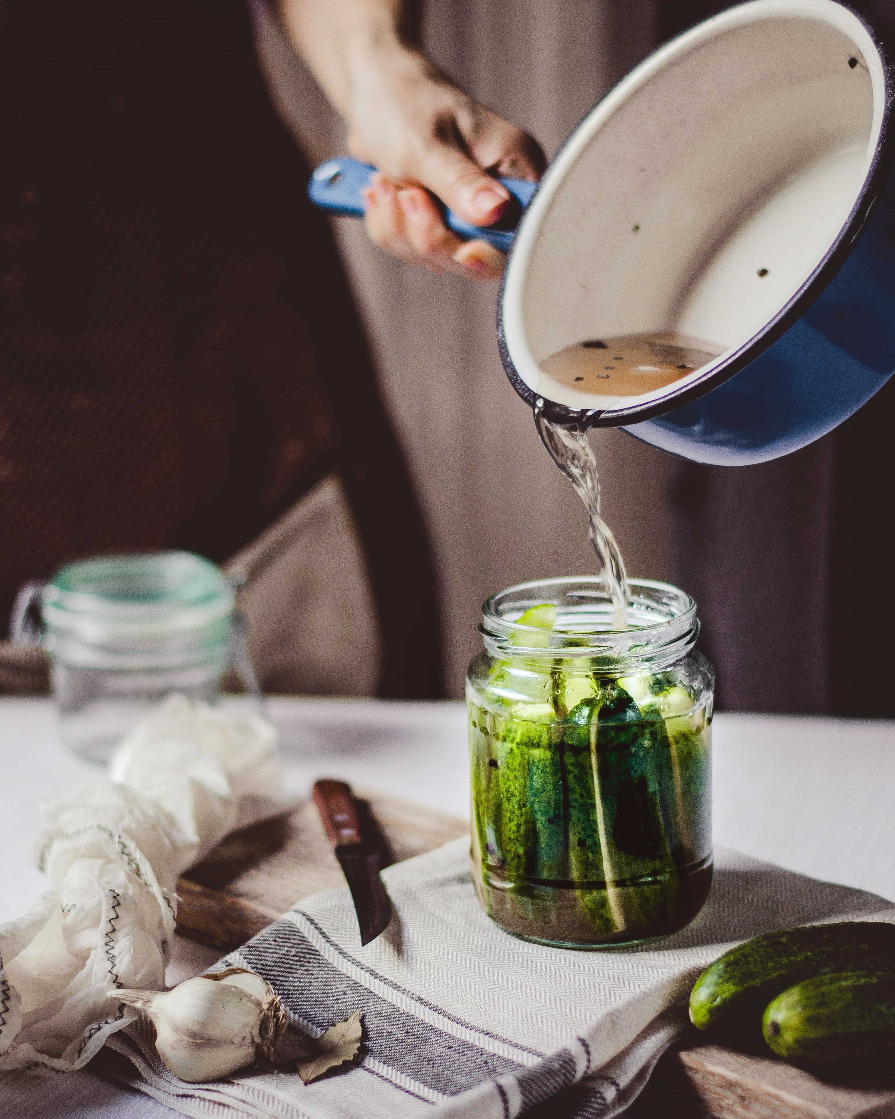 Pouring brine over cucumbers in a jar — fixing mushy, moldy, or slimy fermented vegetables